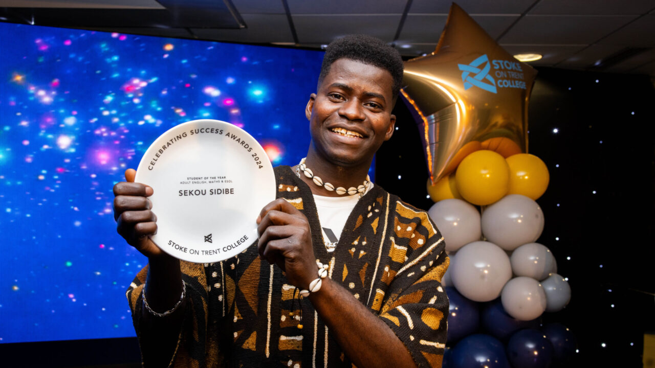 Male collecting award on stage in front of LED screen.