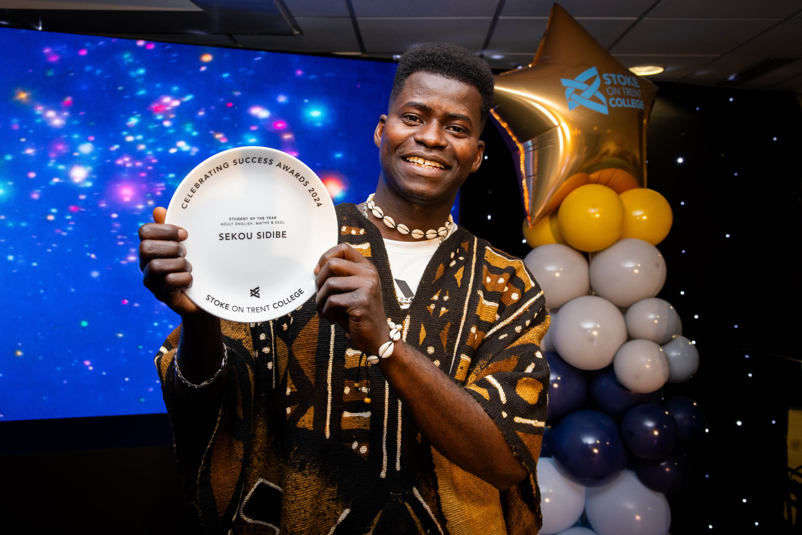 Male collecting award on stage in front of LED screen.
