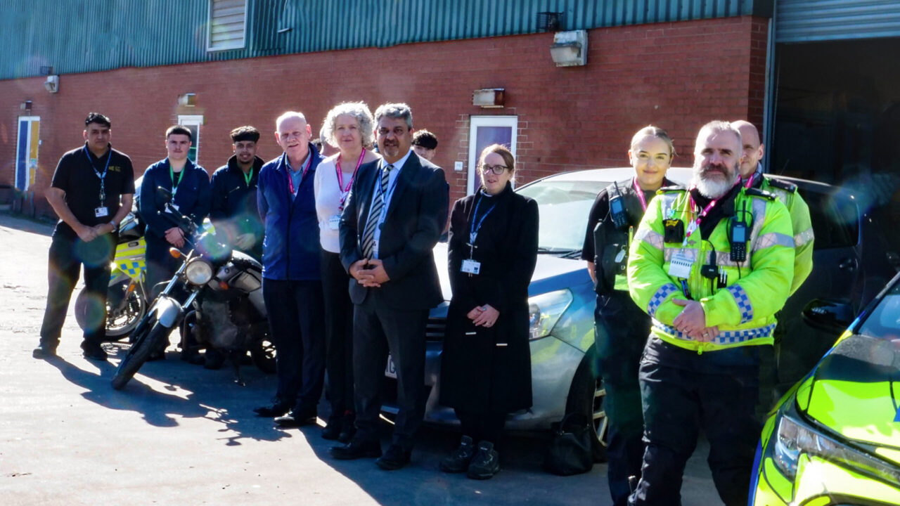 Staff, students, police and guests standing outside the motor vehicle workshop