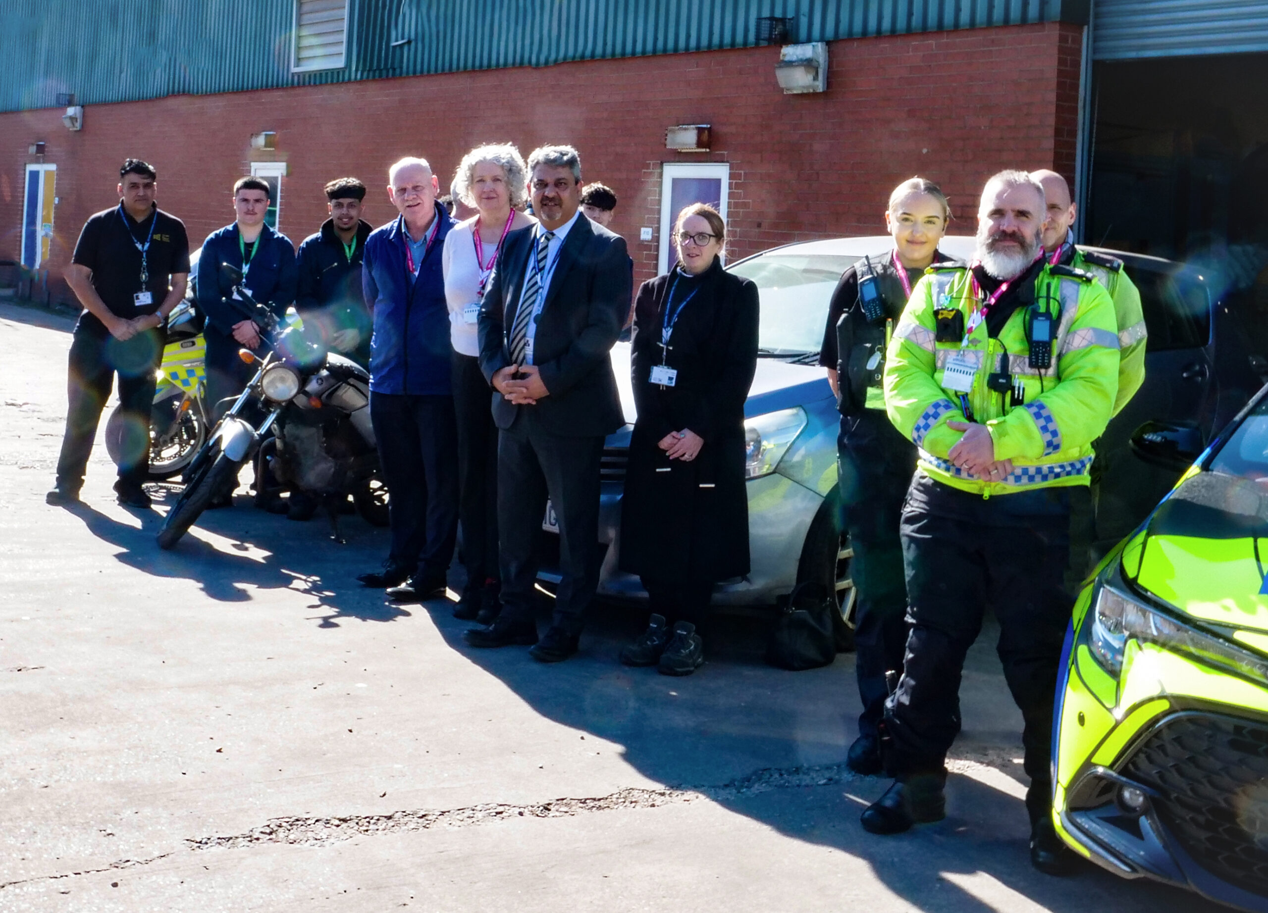 Staff, students, police and guests standing outside the motor vehicle workshop