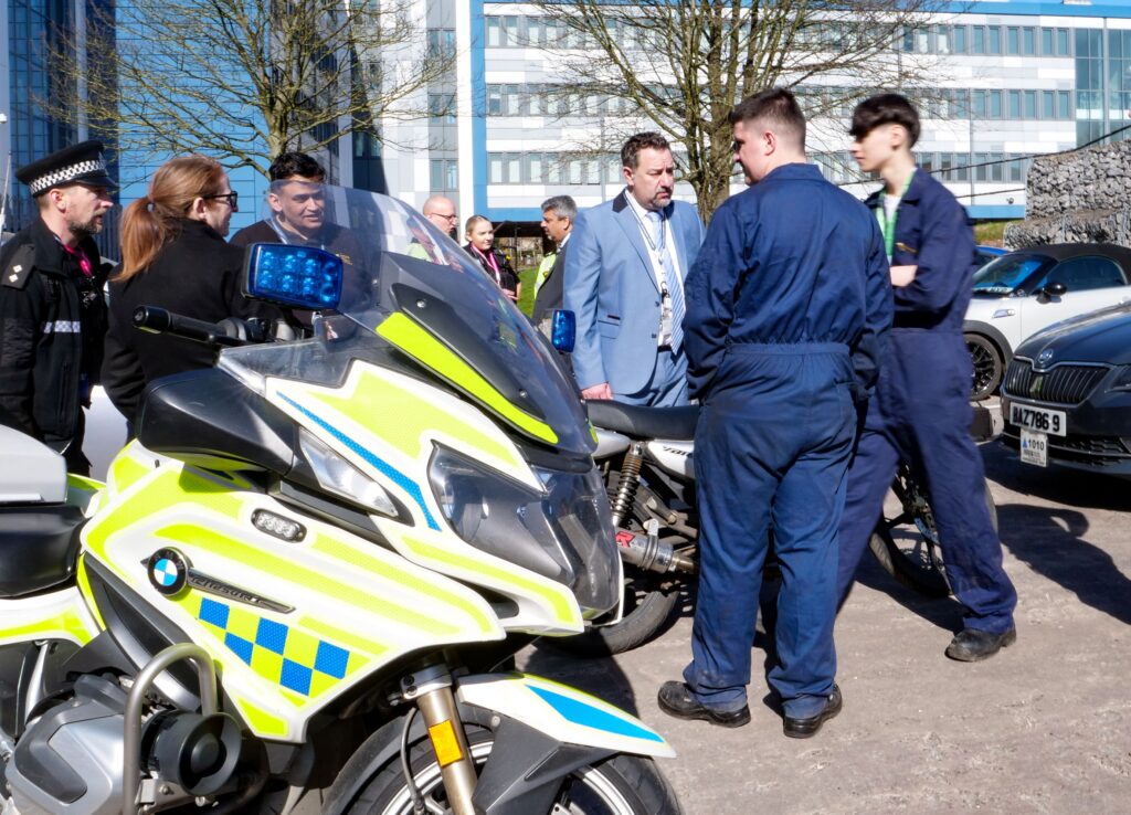 Staff and students gathered outside the workshop with motorbikes